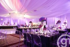 the tables are set up with clear chairs and purple linens for an elegant wedding reception