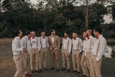 a group of men standing next to each other in front of trees and water with red bow ties