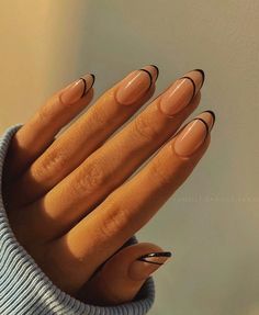 a woman's hand with black and nude nail polish on it, holding her hands in