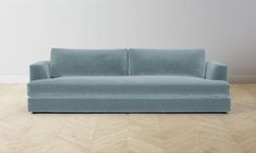 a blue couch sitting on top of a hard wood floor next to a white wall