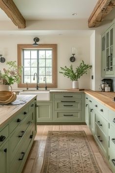 a large kitchen with green cabinets and wooden counter tops, along with a rug on the floor