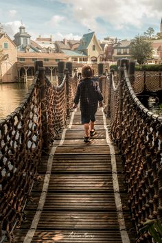 a person walking across a wooden bridge over water