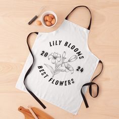 an apron with the words lily blooms best flowers printed on it next to eggs and utensils