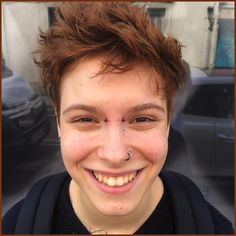 a young man smiling and wearing a black shirt with his nose piercings on it