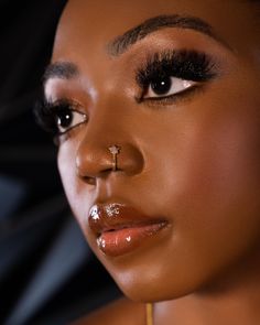 a close up of a woman with makeup on her face and nose piercing in the middle