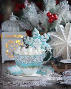 a cup filled with marshmallows sitting on top of a saucer next to a christmas tree