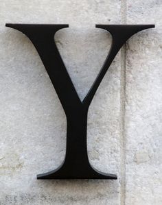 the letter y is mounted to the side of a white wall with black metal letters