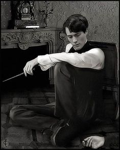 a black and white photo of a young man sitting on the floor with his arm extended