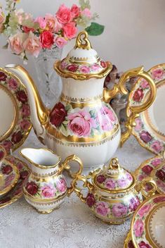 a tea set with pink flowers and gold trimmings