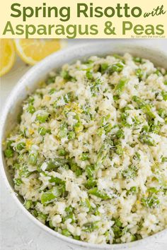 a bowl filled with rice and asparagus on top of a white table next to lemons