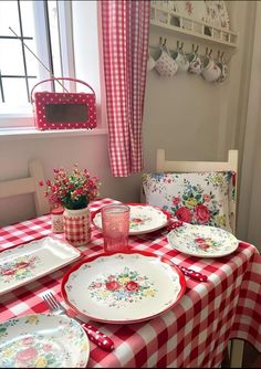 a red and white checkered table cloth on a dining room table set with dishes