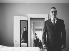 a man in a suit and tie standing next to a bed