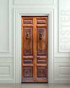 an old wooden door with ornate carvings on the front and side panels, in a white room