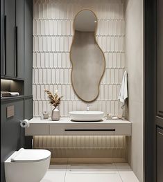 a white toilet sitting next to a sink in a bathroom under a large oval mirror