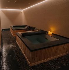 two hot tubs in the middle of a room with lights on either side of them