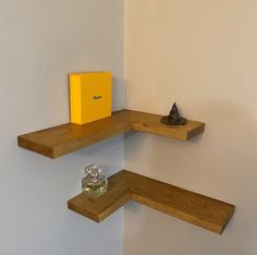 two wooden shelves on the wall, one with a small yellow box sitting on top