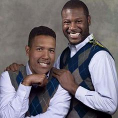 two men in vests are smiling and posing for a photo together with their arms around each other