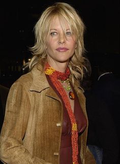 a woman with blonde hair wearing a brown jacket and red neck scarf, posing for the camera