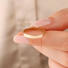 a woman's hand with a gold ring on her finger and the other hand holding it