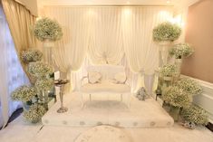 a room with white furniture and flowers in vases on the floor next to it