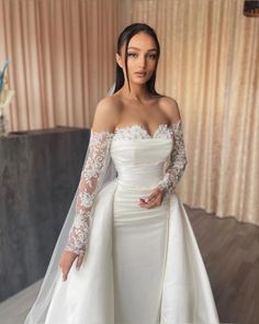 a woman in a wedding dress posing for the camera with her hands on her hips