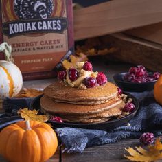 a stack of pancakes topped with berries on top of a table next to pumpkins