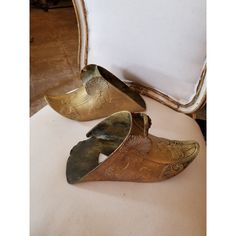 two gold colored shoes sitting on top of a white chair next to a mirror and pillow