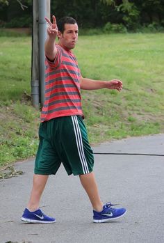 a man in striped shirt and green shorts playing with a frisbee on street