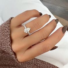 a woman's hand wearing a ring with a diamond in the middle and on her finger