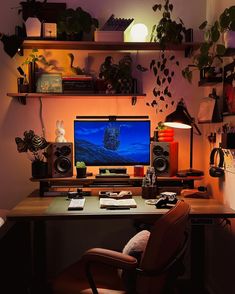 a desk with a computer monitor, keyboard and speakers on it in a dark room