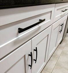 a kitchen with white cabinets and black counter tops