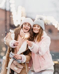 two girls in winter clothes are holding sparklers