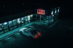 a car parked in front of a donut shop at night