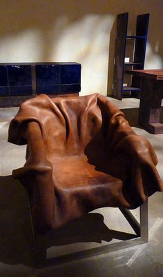 a brown leather chair sitting on top of a cement floor