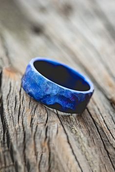 a blue ring sitting on top of a wooden table next to a piece of wood