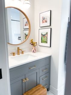 a bathroom with a sink, mirror and pictures hanging on the wall in front of it