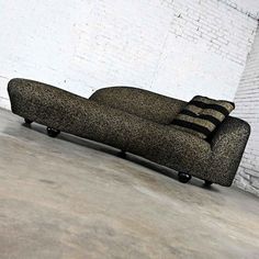 a black couch sitting in front of a white brick wall