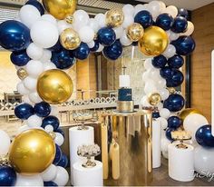 a bunch of balloons that are in the shape of a arch with gold, white and blue balloons