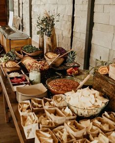 a table filled with lots of food on top of wooden trays next to a brick wall