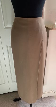 Simply styled with a clean line, this slim skirt has a single, 4" deep, offset front pleat, and a 16" deep back vent for ease in walking. 98% wool, 2% spandex, skirt has a gorgeous, fluid drape. Invisible back zip and hook close. Fully lined, size 4, color Camel. Never worn.  Dimensions: Waist 27" circumference  Hip 37" circumference  35" garment length waist to hem Formal Full-length Pleated Skirt, Elegant High Waist Office Maxi Skirt, Elegant High Waist Maxi Skirt For Office, Formal Full Length Pleated Skirt, Fitted Maxi Skirt For Office, Fitted Knee-length Skirt For Office, Formal Fitted Maxi Skirt, Formal Fitted Long Pleated Skirt, Long Pencil Skirt For Formal Occasions