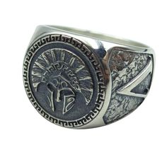 a silver ring with an image of a knight and cross on the front, surrounded by other symbols