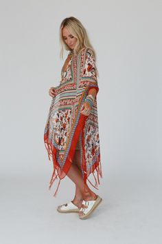 The lightweight Riviera Kimono is gorgeous in this bohemian print with artistic borders, vintage floral, and inviting colors. Inspired tassels adorn the angled knee - length hem, while side slits and wide sleeves give graceful flow to this one - size layer that adds style to every outfit. *Due to lighting and differences in monitors, actual colors may vary slightly from what appears online. Model is 5'8" and wearing a size One Size. Approximate measurements are as follows: ONE SIZE: Bust: 68", A Bohemian V-neck Kimono One Size, Bohemian Kimono For Layering, One Size, Fitted V-neck Bohemian Kimono, Inviting Colors, Bohemian One-size Floral Print Kimono, Multicolor V-neck Kimono With Floral Print, Bohemian Print, Print Kimonos, Border Print