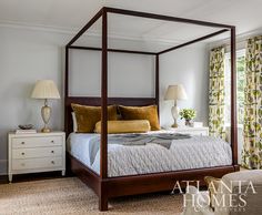 a four poster bed in a bedroom next to two lamps