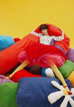 a woman laying on top of a pile of pillows