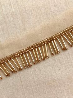 a gold colored metal chain with holes in the middle on a white fabric background, closeup