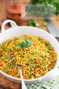 barley pilaf with peas and carrots in a white bowl on a wooden cutting board