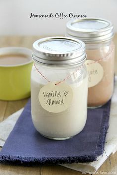 three jars filled with vanilla almond coffee creamer on top of a blue napkin next to a cup of coffee