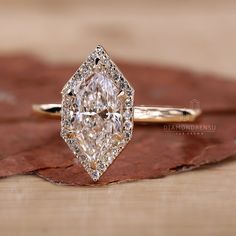 a diamond ring sitting on top of a wooden table next to a brown and white leaf