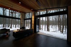 a living room filled with furniture and large windows covered in frosty snow next to trees