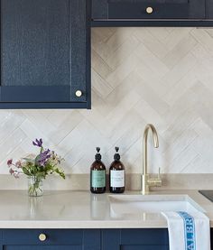 a kitchen with blue cabinets and white counter tops, along with a vase filled with flowers